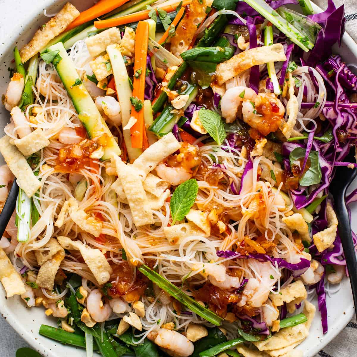 Salada colorida com quinoa, grão-de-bico, tomate cereja, abacate e folhas verdes, acompanhada de garrafa de água e garfos de bambu