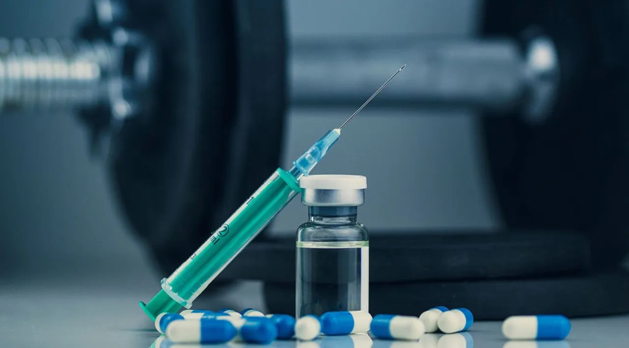 Vial de laboratório com solução transparente ao lado de um haltere e um frasco de suplemento, sugerindo uso de peptídeos no esporte