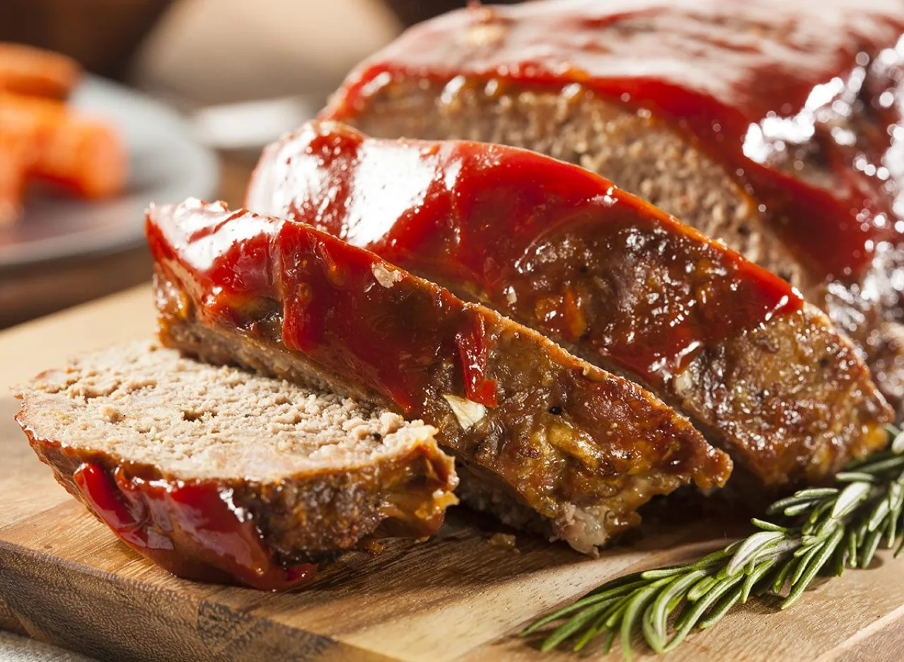 Prato de madeira com carne moída rosada, pedaços de gordura visíveis, alho, cebola e folhas de salsa ao lado