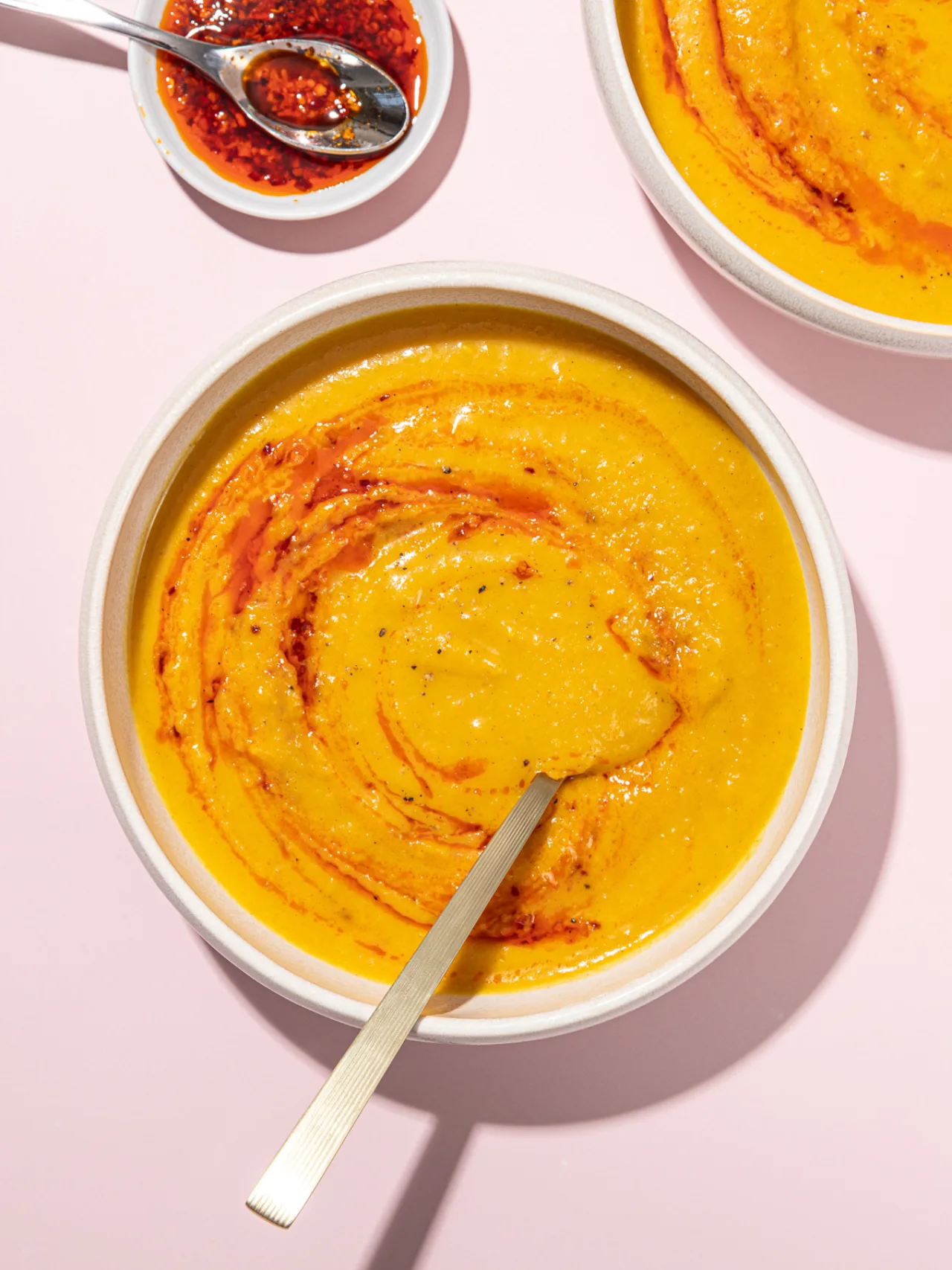 Tigela de sopa cremosa de abóbora com feijão branco, leite de coco, folhas de coentro e colher de madeira