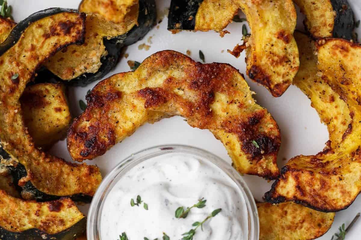 Metade de abóbora acorn temperada com azeite, mel e parmesão, disposta na cesta da air fryer, dourando