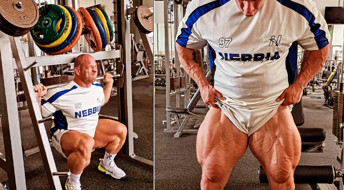 Krizo executa agachamento na Smith Machine, com barra carregada, joelhos dobrados e camisetas esportivas, ao fundo há hack squat