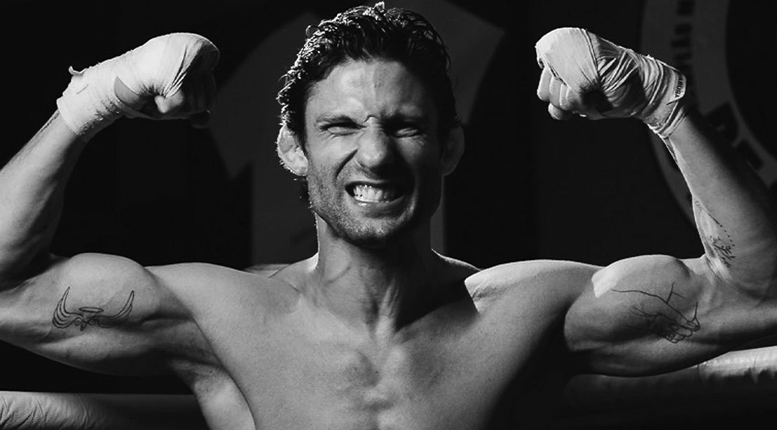 Um atleta em treinamento intenso, com uma garrafa de água e um suplemento de proteína ao lado