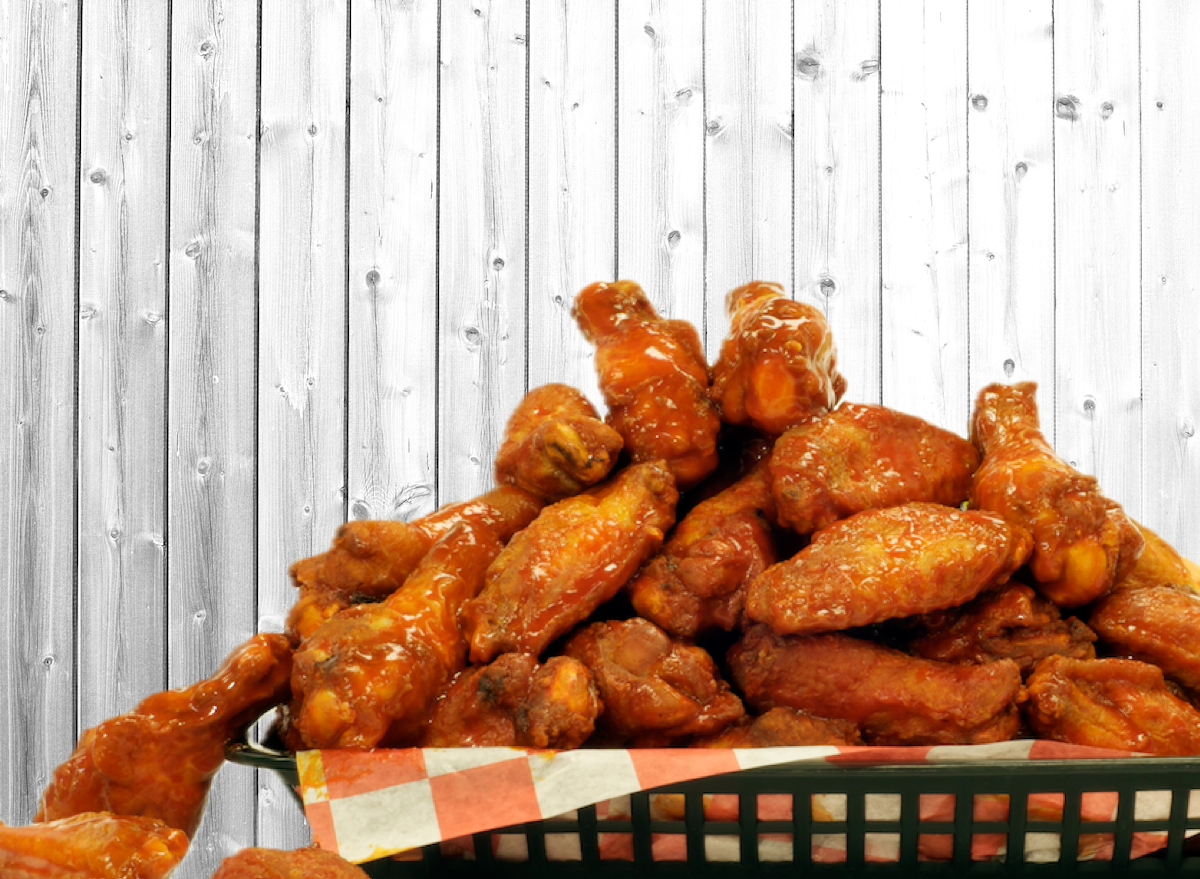 Uma asa de frango com osso grelhada ao lado de uma colher e um copo de água