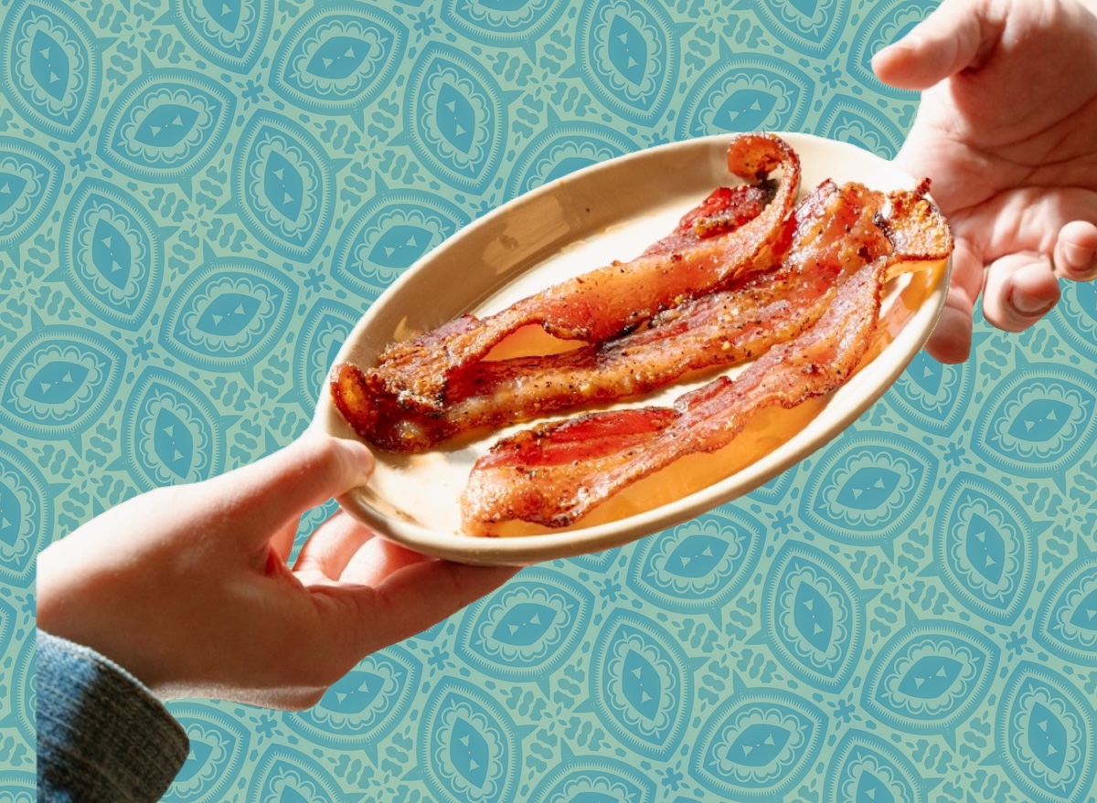 Um prato de ovos fritos ao lado de fatias de bacon crocante e uma xícara de café