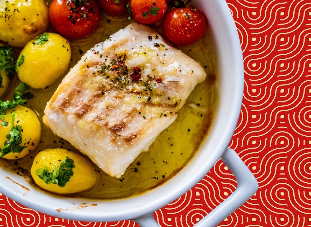 Filé de bacalhau assado ao lado de brócolis no vapor, quinoa e limão sobre mesa de madeira