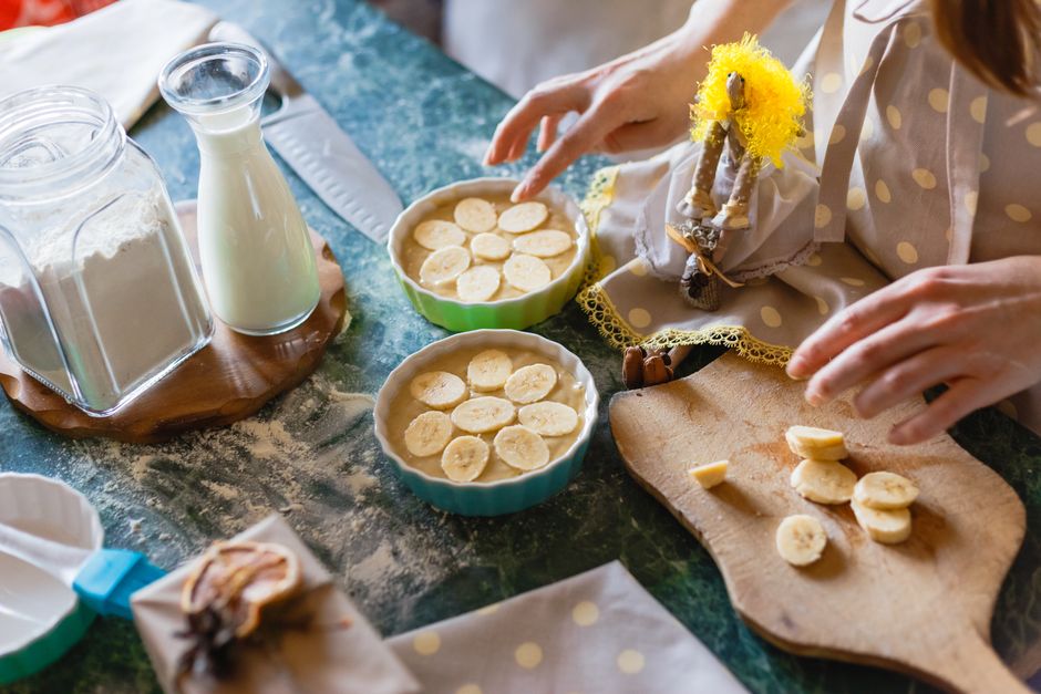 Taça de banana pudding com camadas de pudim, rodelas de banana e biscoitos, coberta por chantilly ao lado de uma balança