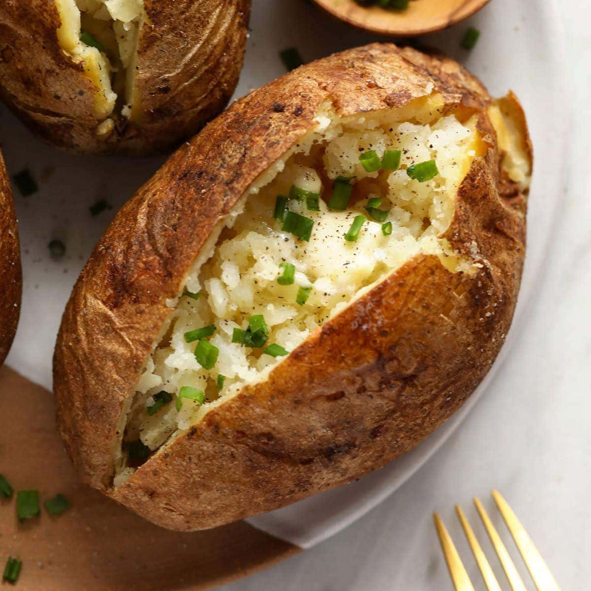 Uma batata assada no forno com pele crocante e interior macio, unida com azeite e sal grosso