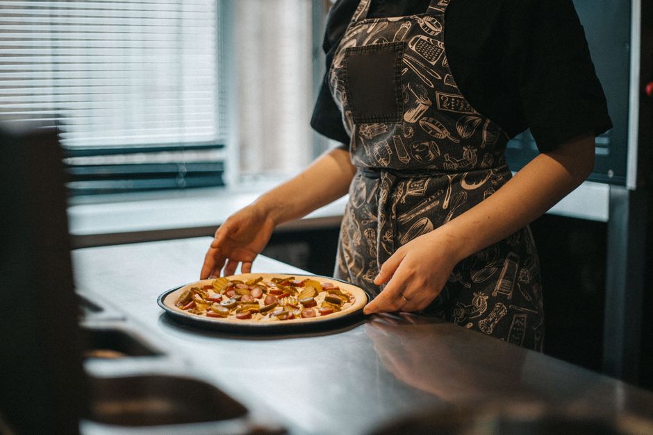 Pizza de frango ao barbecue sobre massa integral, com folhas de rúcula e fatias de tomate ao lado