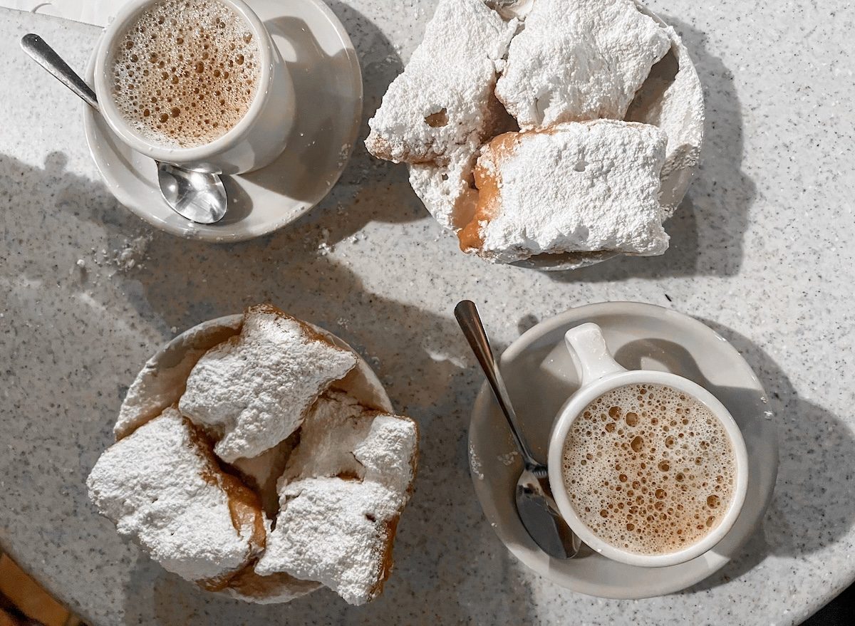 Massas fritas cobertas com açúcar de confeiteiro sobre uma tigela de café