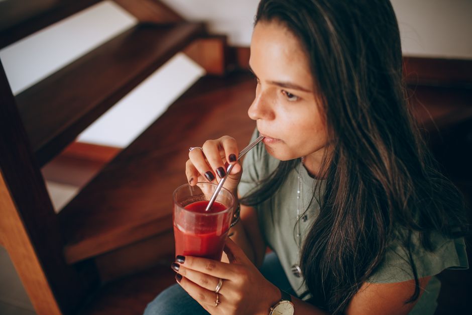 Uma garrafa de suco de beterraba fresca em uma mesa de madeira com um liquidificador ao fundo