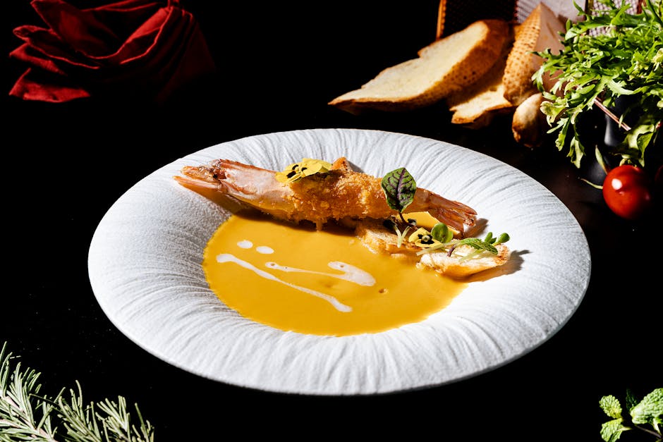 Prato fundo com bisque de lagosta cremosa, decorado com ervas frescas e uma cauda de crustáceo sobre mesa elegante