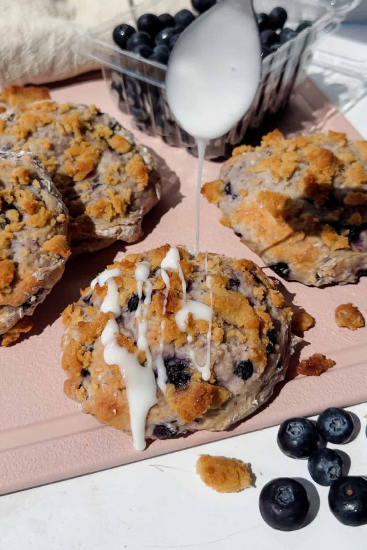 Um prato de biscoitos de blueberry com cottage cheese, cobertos com streusel crocante e uma assadeira de papel manteiga ao fundo