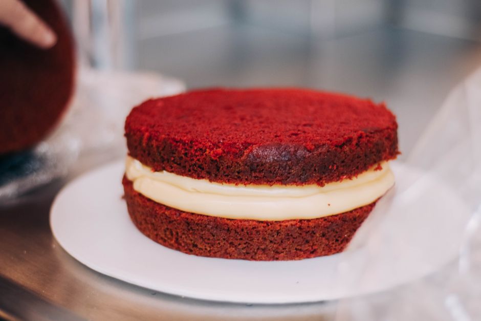Fatia de Boston Cream Pie ao lado de uma balança, copo de água e maçã verde sobre mesa de madeira