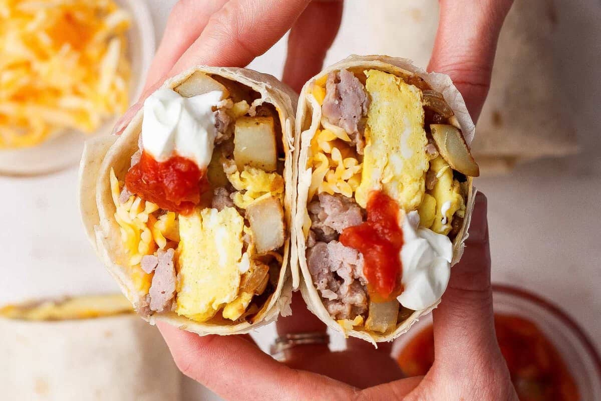Um burrito de ovos, bacon e queijo, envolto em uma tortilha, com uma xícara de suco de laranja ao lado