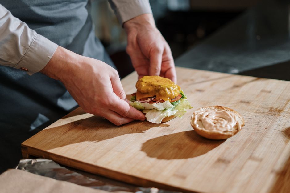 Homem musculoso segurando um butterburger suculento, com pão dourado e manteiga escorrendo