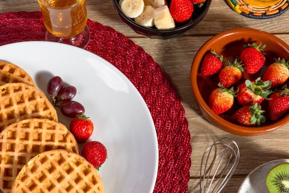 Uma pessoa comendo um omelete de ovos com legumes e frutas, acompanhado de um copo de suco de laranja