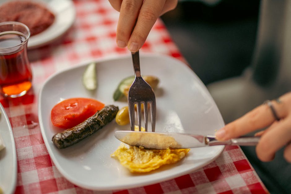 Prato com ovos mexidos, abacate fatiado, aveia com frutas e uma xícara de café sobre uma mesa de madeira iluminada