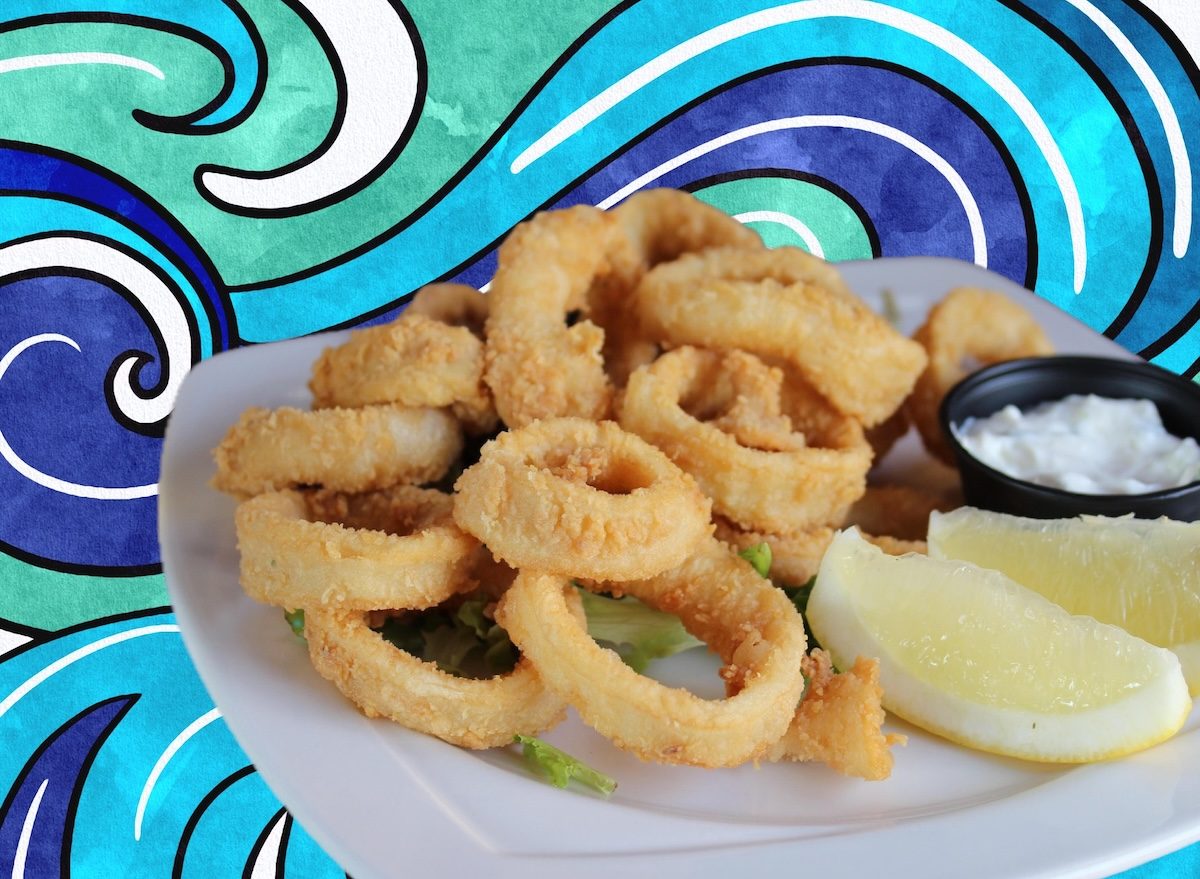 Um prato de calamari frito com batatas fritas e uma cerveja à beira da praia