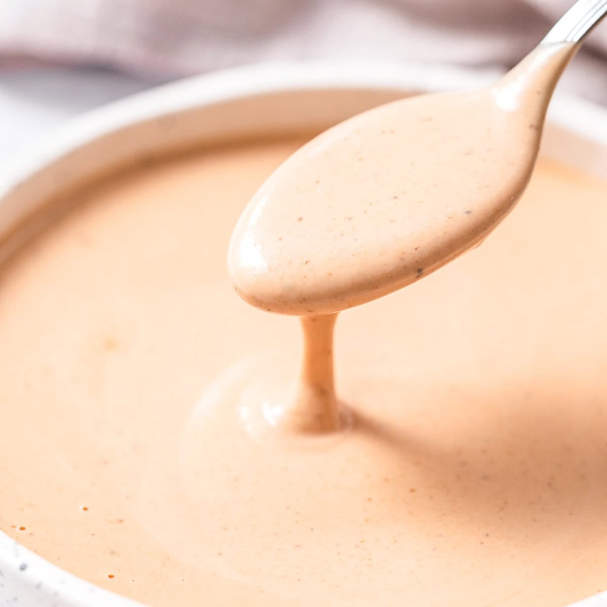 Uma garrafa de maionese integral, ketchup e molho inglês estão sobre uma bancada de cozinha
