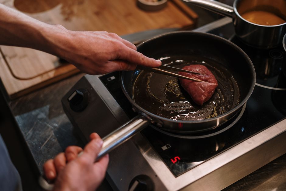 Uma panela de estew de carne enlatada é exibida ao lado de uma garrafa de água e um prato de frutas frescas