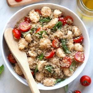 Quinoa, tomate, queijo e folhas de alface fresca em uma bandeja de madeira