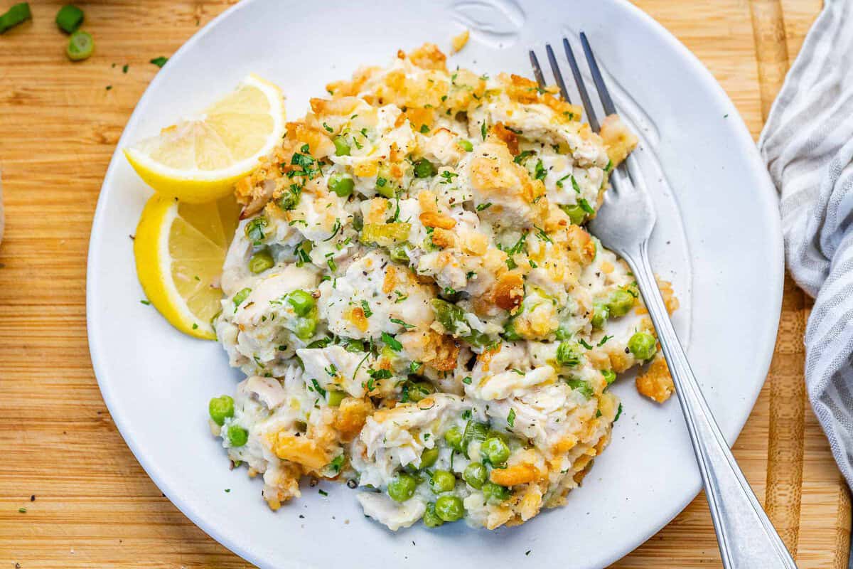 Prato de casserole de frango desfiado com ervilhas e cobertura de biscoito salgado dourado, em travessa de cerâmica branca