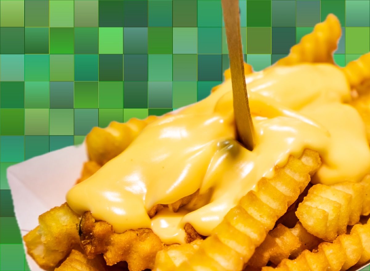 Batatas fritas crocantes cobertas com molho de queijo derretido e ervas frescas