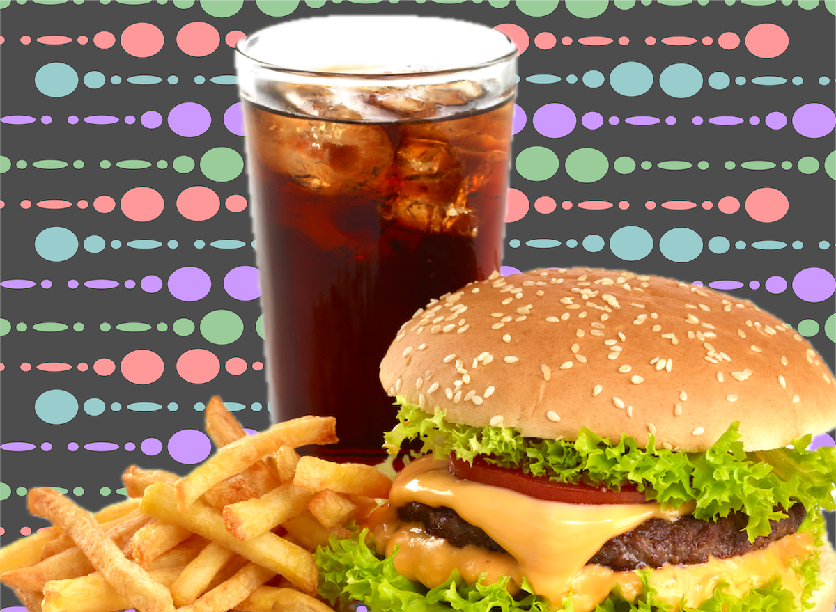 Um cheeseburger com batata frita, com vegetais frescos e folhas verdes, em segundo plano
