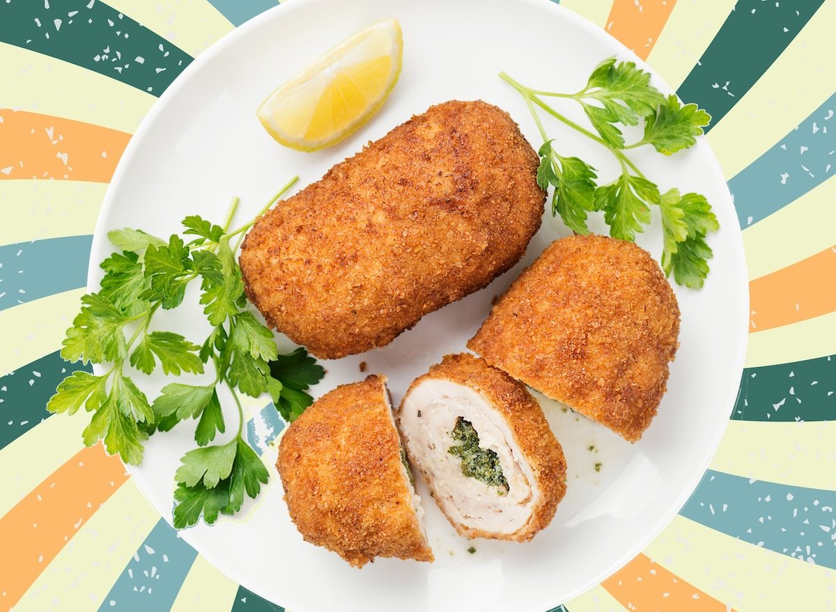 Peito de frango Kiev congelado ao lado de uma balança de cozinha, legumes grelhados e um copo de água
