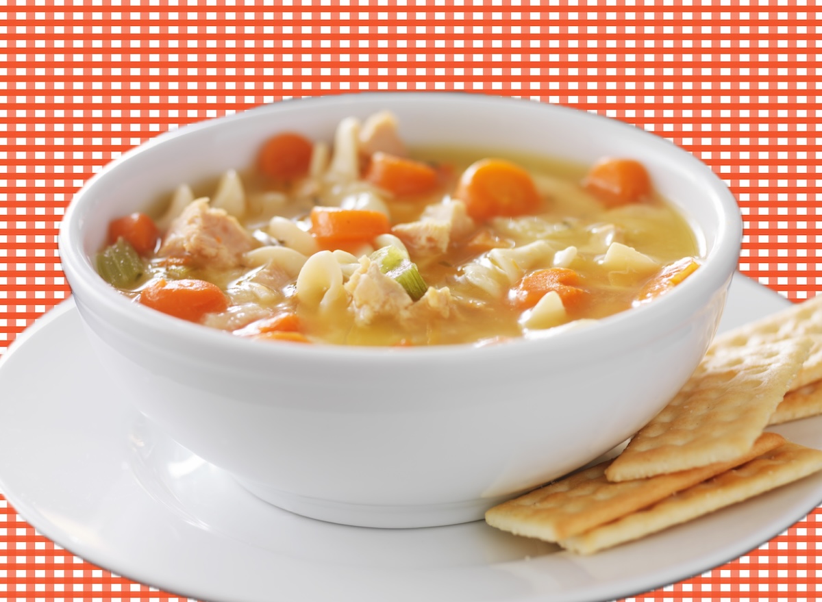 Uma tigela de sopa de galinha com noodles, legumes frescos e pedaços de carne tenra