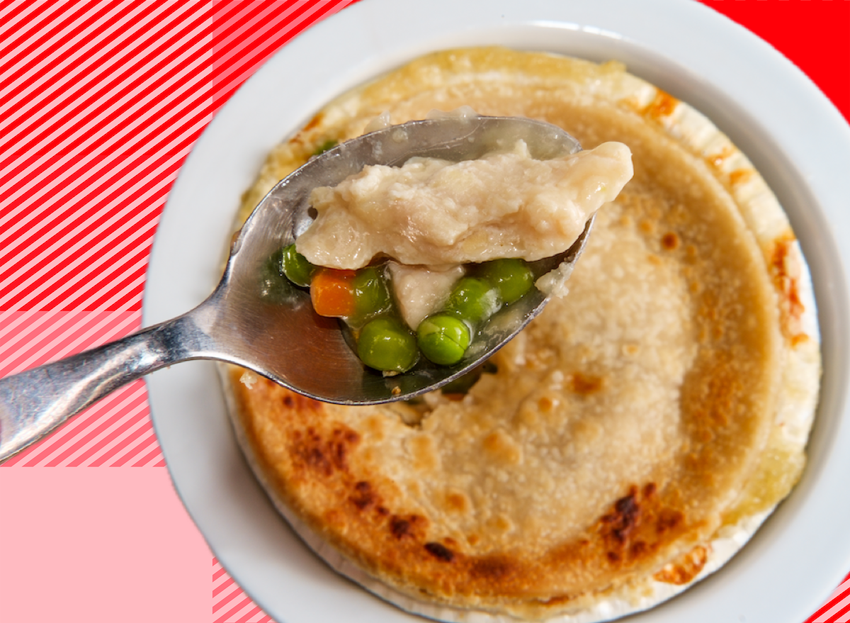 Uma imagem de um prato de Chicken Pot Pie congelado, com uma fatia cortada e um copo de água ao lado