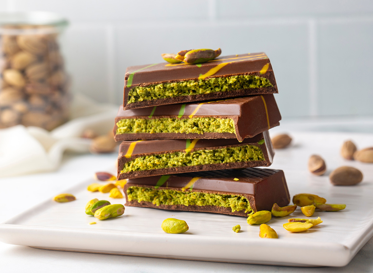 Barra de chocolate recheada com creme de pistache e massa crocante partida ao meio sobre uma mesa de mármore