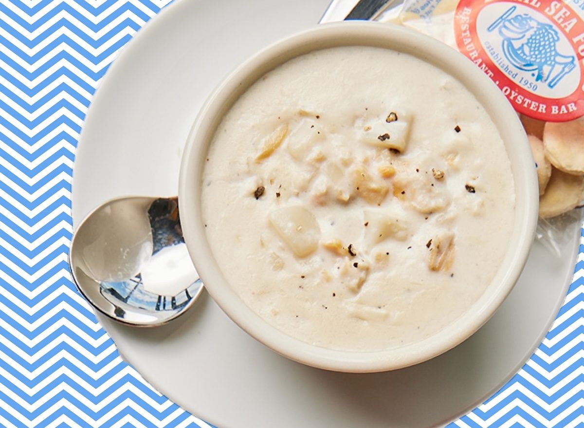 Uma tigela de sopa cremosa de clams, batatas e creme em uma panela de fundo branco