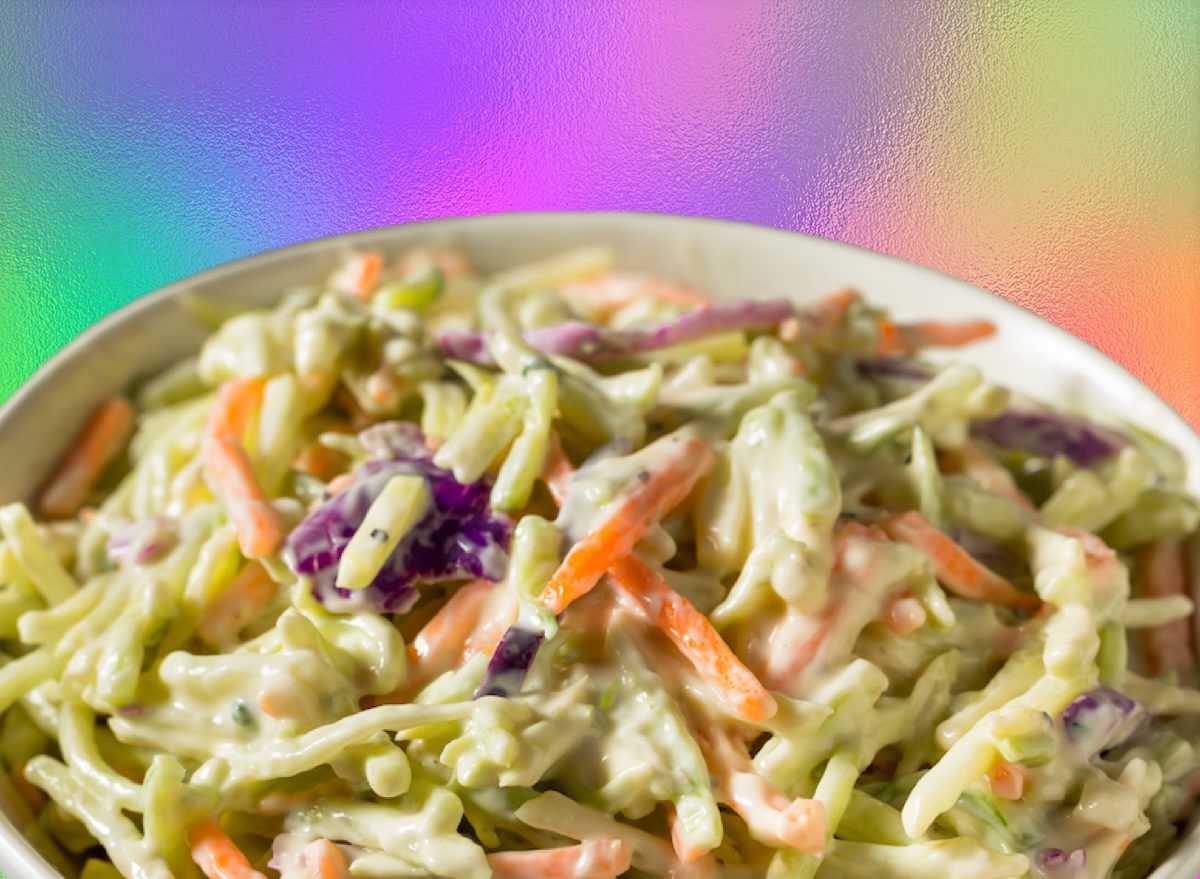 Uma pessoa segurando uma tigela de coleslaw fresco com repolho e molho cremoso