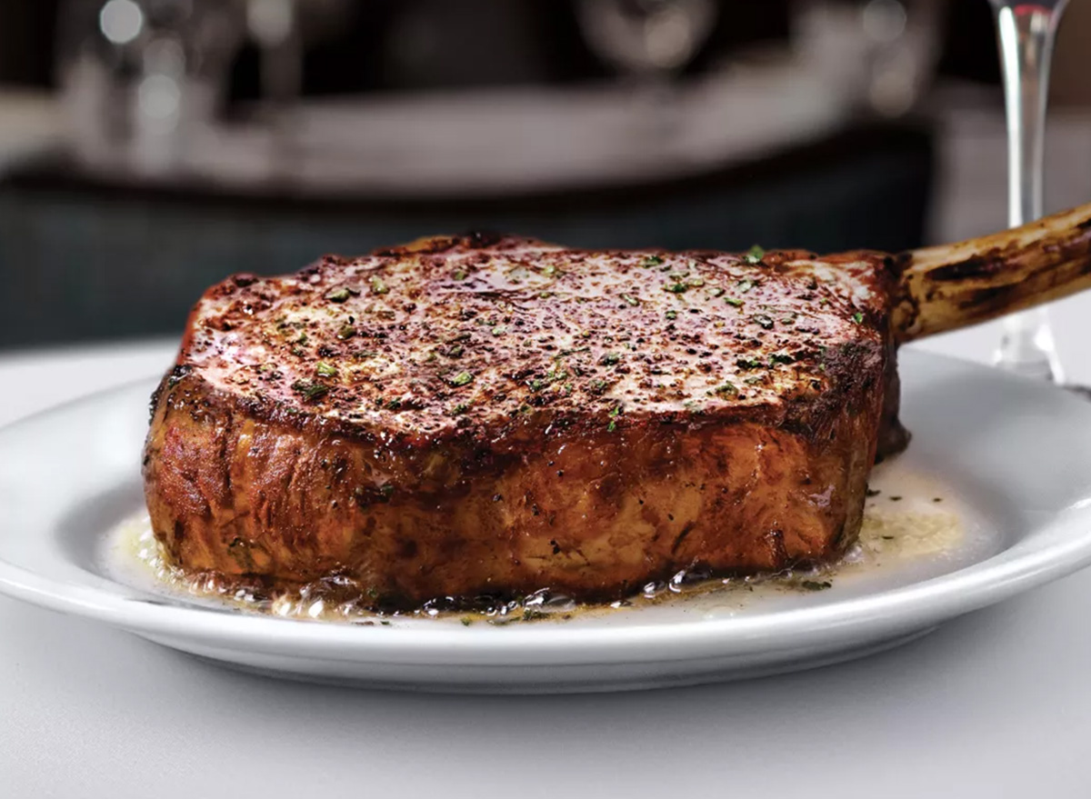 Um bife de ribeye suculento sendo preparado em uma frigideira de ferro com alecrim e alho sobre uma bancada gourmet