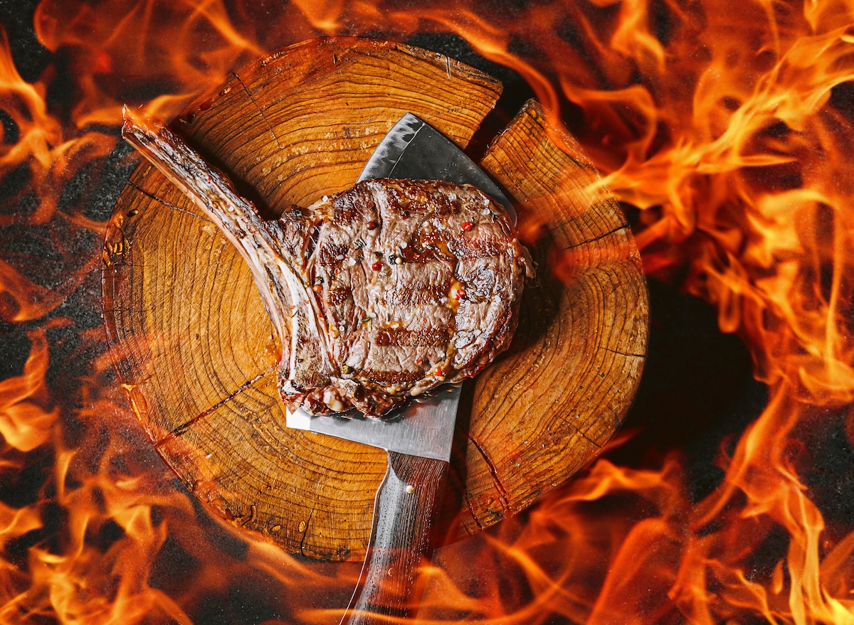 Picanha suculenta grelhando sobre brasas quentes em uma churrasqueira com pinças de metal ao lado