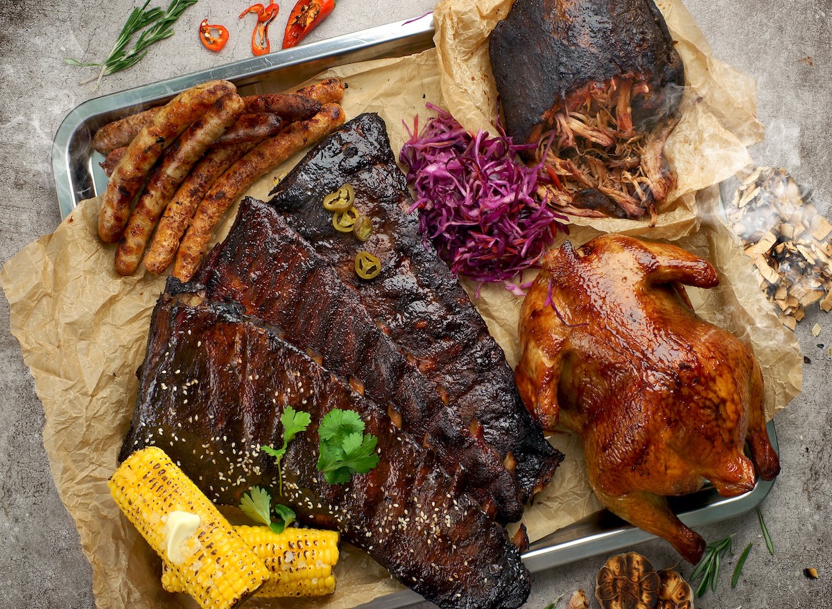 Prato com cortes de carne magra, espeto de legumes grelhados e salada verde fresca sobre uma mesa de madeira