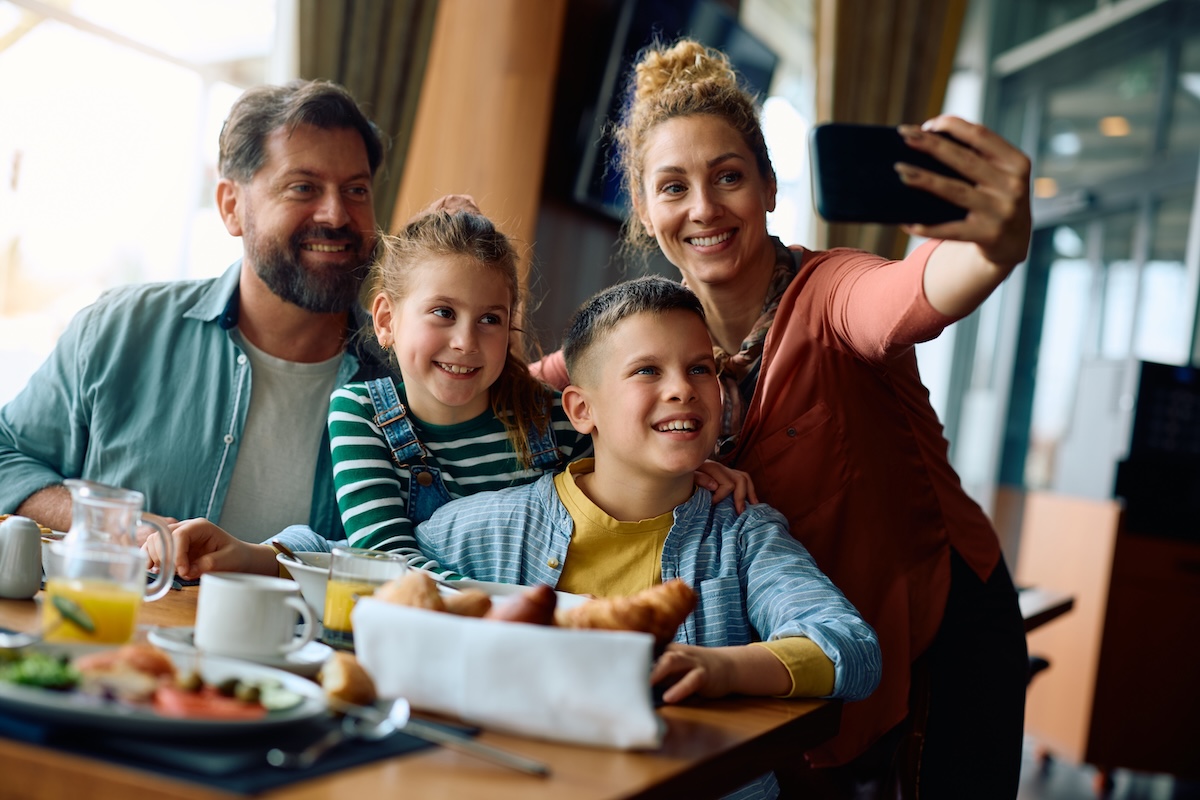 Família sorridente compartilhando pratos com saladas frescas e proteínas grelhadas em um restaurante aconchegante
