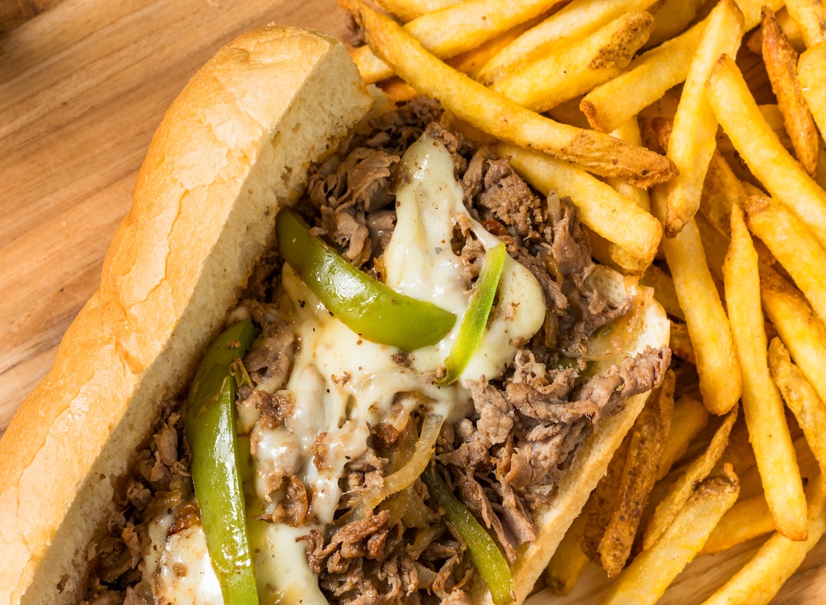Sanduíche de carne artesanal em pão integral com salada fresca e uma garrafa de água sobre uma mesa de madeira