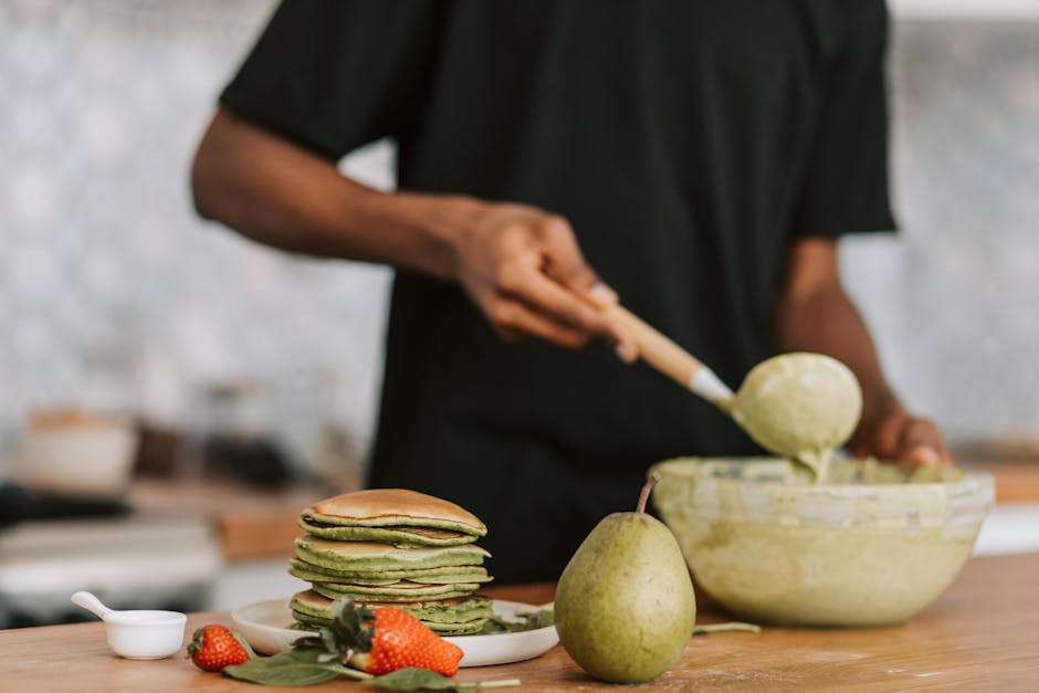 Pilha de panquecas fofinhas em um prato, decoradas com frutas frescas e mel, sobre uma mesa de café da manhã