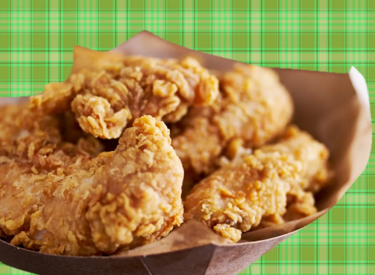 Tiras de frango douradas e crocantes dispostas em uma tábua de madeira, acompanhadas por um molho cremoso ao lado