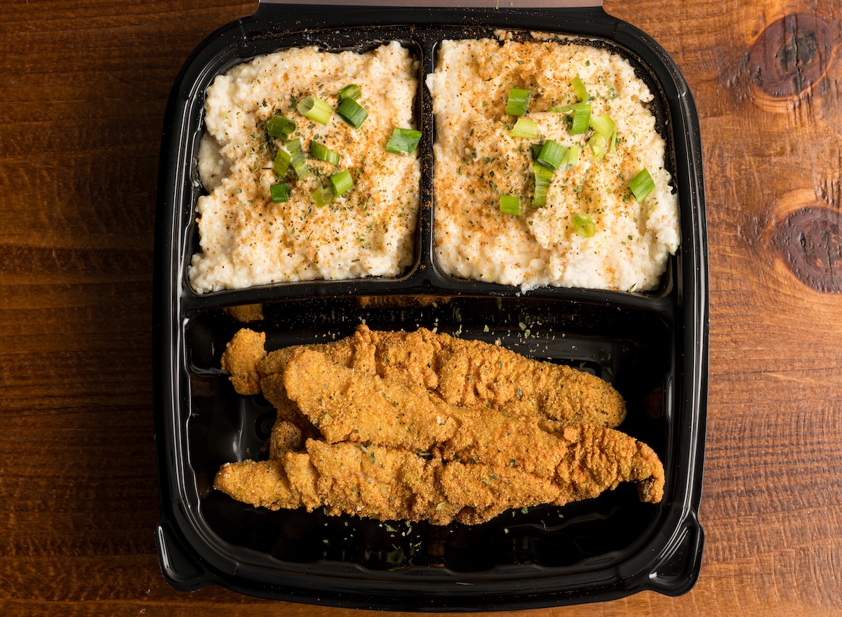 Filé de peixe dourado e crocante em uma airfryer, acompanhado de rodelas de limão e ervas frescas sobre uma mesa