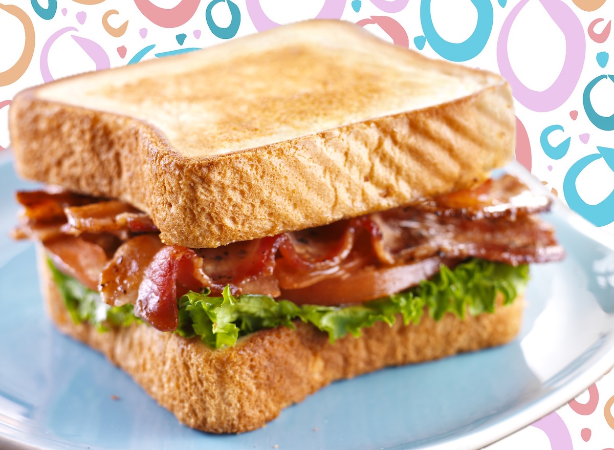 Sanduíche BLT montado com fatias de bacon crocante, alface fresca e tomates suculentos sobre uma tábua de madeira