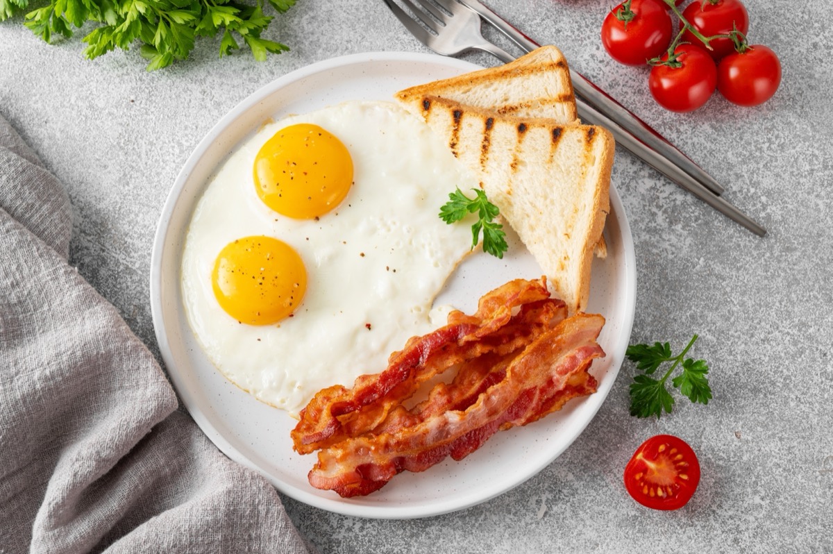 Ovos frescos sobre uma mesa de restaurante ao lado de um prato com omelete caseira e ingredientes naturais