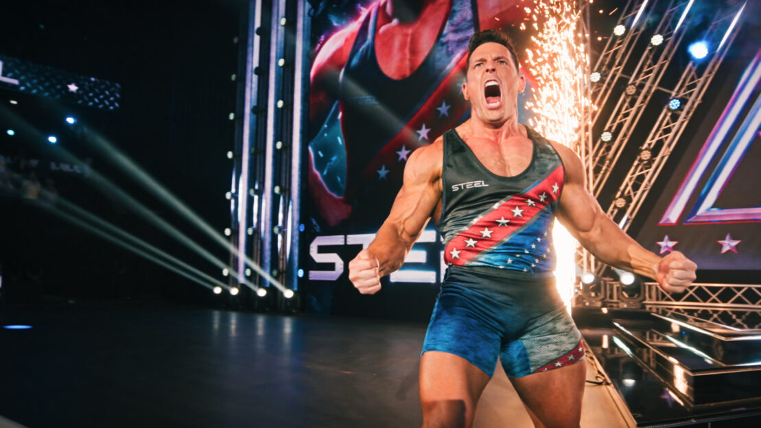 Jessie Godderz realizando um exercício intenso de levantamento de peso em uma academia com equipamentos modernos