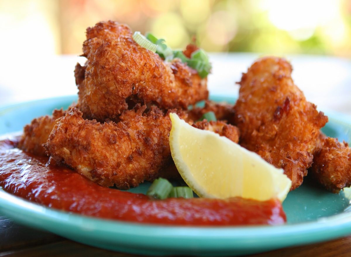 Um frango de concha empanado e frito, com um corte de limão e folhas de coentro ao lado