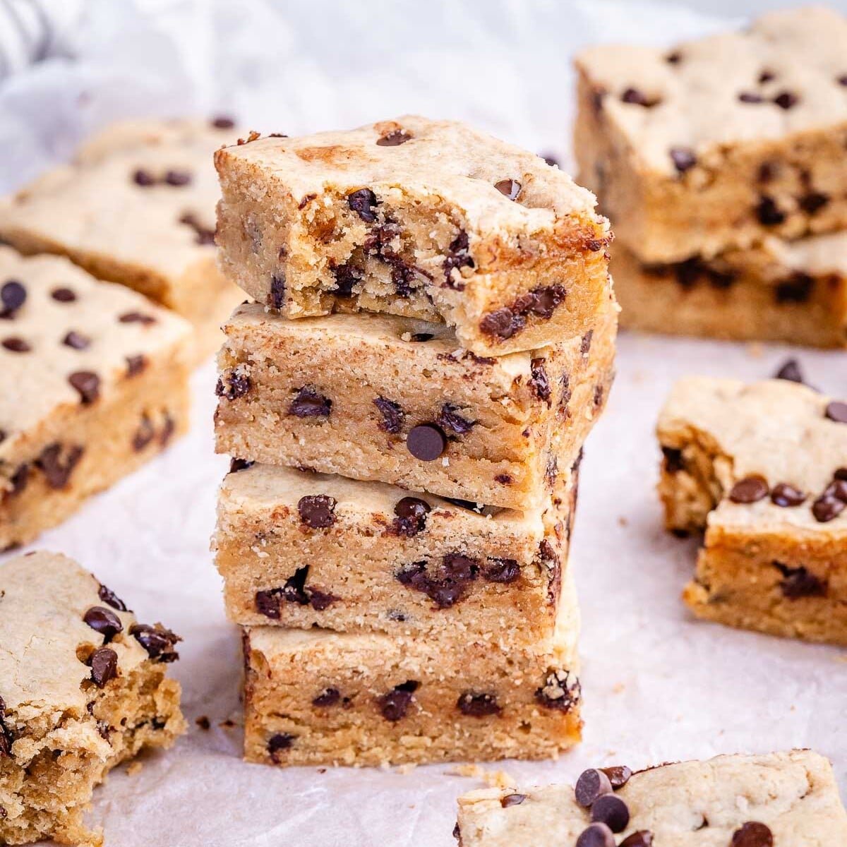 Uma mulher segurando um cookie de chocolate ao lado de uma barra de cereal integral