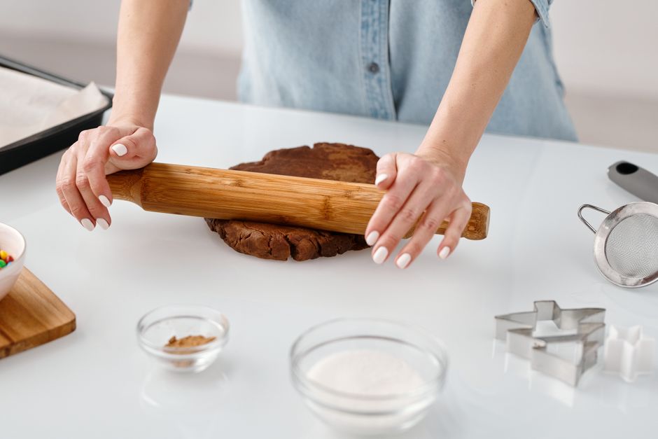 Um prato de cookies dourados ao lado de um copo de água e uma balança de cozinha