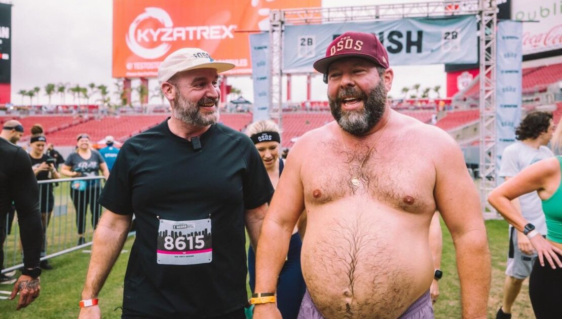 Tom Segura correndo em uma pista ao ar livre, vestindo roupas esportivas modernas e um relógio de monitoramento